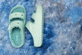 pair of green Crocs sandals with faux fur on blue background. View from above. Space for text