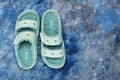 pair of green Crocs sandals with faux fur on blue background. View from above. Space for text