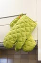 Pair of green kitchen gloves hanging on a cupboard handle. Royalty Free Stock Photo