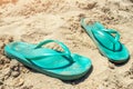 A pair of green shabby slippers on the hot beach sand Royalty Free Stock Photo