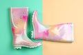 Pair of gumboots on color background, top view