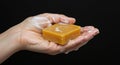 A pair of hands holds a rectangular bar of orange soap, lathered with white Royalty Free Stock Photo