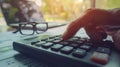 A pair of hands operates a calculator next to eyeglasses and financial documents on a desk..AI generated image Royalty Free Stock Photo