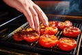 a pair of hands picking up a grilled tomato from a tray
