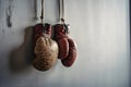 Pair of hanging old boxing gloves isolated on grey wall background. Royalty Free Stock Photo