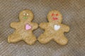 Pair of happy gingerbread men with candy hearts and raw transparent glaze on baking paper. Making homemade smiling cookies