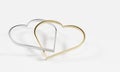 Pair of heart shape metal silver and gold rings tie together.