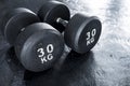 A pair of heavy 30 kilogram dumbbells on rubber floor matting at the gym. Made with cast iron and coated with rubber. Royalty Free Stock Photo