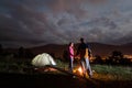 Pair holding hands, standing near camp, looking at each other