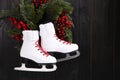 Pair of ice skates and beautiful Christmas wreath hanging on dark wooden wall, space for text Royalty Free Stock Photo