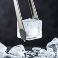 A pair of ice tongs gripping a translucent ice block