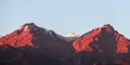 A pair of identical peaks of the mountains of the Zailiysky Alatau in the early morning, illuminated in orange colors Royalty Free Stock Photo