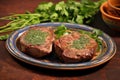 pair of juicy chops garnished with cilantro leaves on clay plate