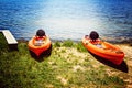 A pair of kayaks at the edge of a sunlit lake