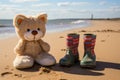 pair of kids boots and a soft toy on a sandy beach Royalty Free Stock Photo