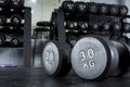 A pair of 30 kilo dumbbells on the floor with a dumbbell rack at the background.