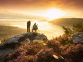 Pair of landscape photographers standing on cliff, taking photos of misty landscape