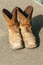 Pair of leather cowboy boots, covered in dirt and chalk Royalty Free Stock Photo