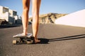 Pair of legs barefoot young woman ready to start with the skateboard on the asphalt. sunny day of vacation and alternative way to