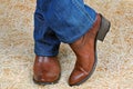 Pair of legs in cowboy boots and jeans on straw Royalty Free Stock Photo