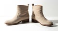 A pair of light beige ankle boots with a low heel, set against a bright white background. Royalty Free Stock Photo