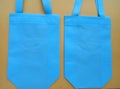 A pair of light blue tote bags on a brown background