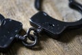 A pair of locked handcuffs without a key, lying on a textured wooden board with space to copy. Royalty Free Stock Photo