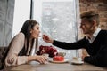 A pair of lovers, a man and a woman, eat with spoons a red heart-shaped dessert in a cafe. Royalty Free Stock Photo