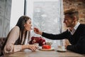 A pair of lovers, a man and a woman, eat with spoons a red heart-shaped dessert in a cafe. Royalty Free Stock Photo