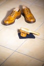 Pair of Luxury Male Full Brogued Tan Oxford Shoes. Placed Together with Shoe wax and Brush on Tiles Floor Royalty Free Stock Photo