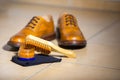 Pair of Male Full Brogued Tan Oxford Shoes. Placed Together with Shoe wax and Brush on Tiles Floor Royalty Free Stock Photo