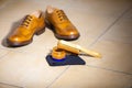 Pair of Male Full Brogued Tan Oxford Shoes. Placed Together with Shoe wax and Brush on Tiles Floor Royalty Free Stock Photo