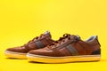 Pair of male's new sneakers made of brown leather on a yellow background. Copy space