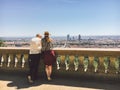 A pair of man and woman stand with their backs and look at the panoramic view from the high point to the city of Lyon in France in