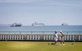 Pair of mature ladies playing bowls in front of collection of large cruise ships moored in Weymouth Bay because of Coronavirus -