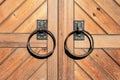 a pair of metal rings on a wooden door handle on a wooden door with a wooden plank pattern behind it Royalty Free Stock Photo