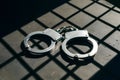Metallic handcuffs on surface, sharp shadows, grid like shadow pattern Royalty Free Stock Photo