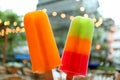 Pair of mix fruit popsicles with blurry urban evening view