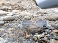 A pair of modern, stylish, and trendy sunglasses or shades or sunnies on the top of a rock in a stream of water with beautiful