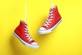 Pair of new stylish red sneakers hanging on laces against yellow background Royalty Free Stock Photo