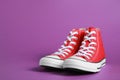 Pair of new stylish red sneakers on purple background. Space for text Royalty Free Stock Photo
