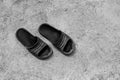 A pair of old black rubber sandals on the cement floor.