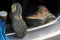 Pair of old brown hiking shoes on a car boot and cup of coffee to go. Reliable leather worn out boots. Long walk or travel trip Royalty Free Stock Photo