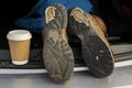 Pair of old brown hiking shoes on a car boot and cup of coffee to go. Reliable leather worn out boots. Long walk or travel trip Royalty Free Stock Photo