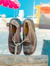 Pair of old brown leather shoes tied together with shoelaces hanging at the old vintage wooden pole at the sandy beach. Used Royalty Free Stock Photo