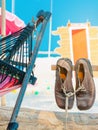 Pair of old brown leather shoes tied together with shoelaces hanging at the old vintage wooden pole at the sandy beach. Used Royalty Free Stock Photo