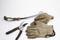 Old gloves, clippers and a red rose on a white background