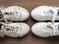 Pair of old dirty white sneakers in front of new clean one on a brown background. Past and future, old and new concepts.