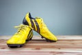 Old yellow football shoes placed on a wooden board, gray background Soft light Royalty Free Stock Photo