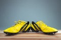 Old yellow football shoes placed on a wooden board, gray background Soft light Royalty Free Stock Photo